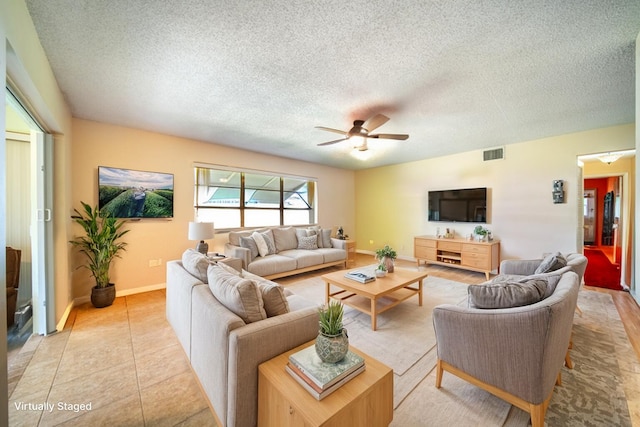 living room featuring ceiling fan, light tile patterned floors, and a textured ceiling