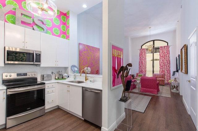 kitchen with white cabinetry, pendant lighting, sink, appliances with stainless steel finishes, and dark wood-type flooring