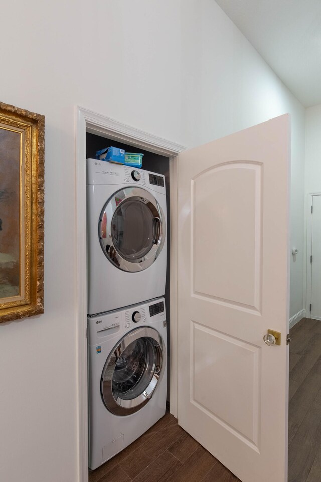 clothes washing area featuring stacked washer and dryer and dark wood-type flooring