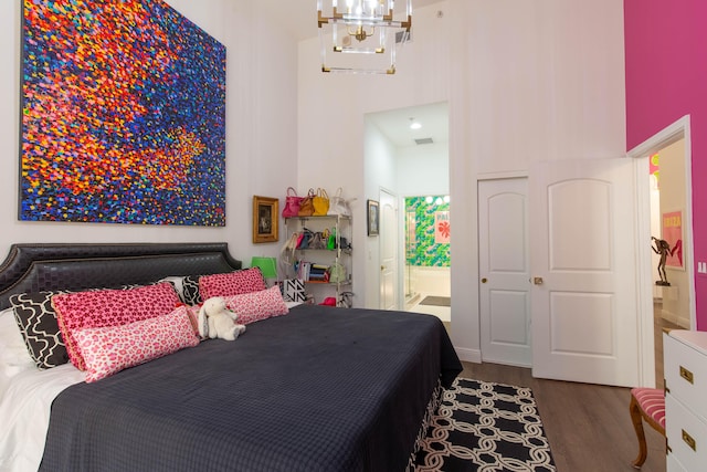 bedroom with dark hardwood / wood-style flooring, connected bathroom, and a notable chandelier