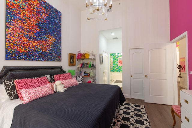 701 S Olive Ave Unit 409, West Palm Beach, FL 33401 - bedroom with ensuite bath, a towering ceiling, an inviting chandelier, and wood finished floors