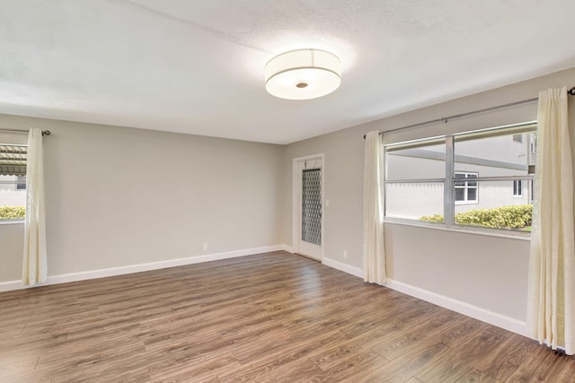 unfurnished room featuring a healthy amount of sunlight, wood-type flooring, and a textured ceiling