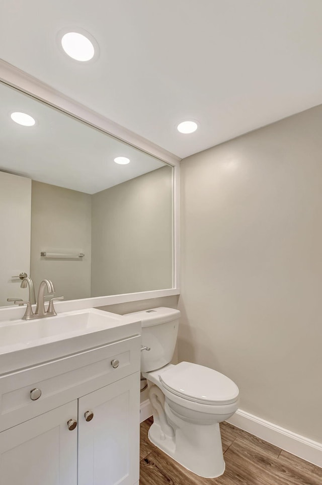 bathroom with toilet, vanity, and hardwood / wood-style flooring