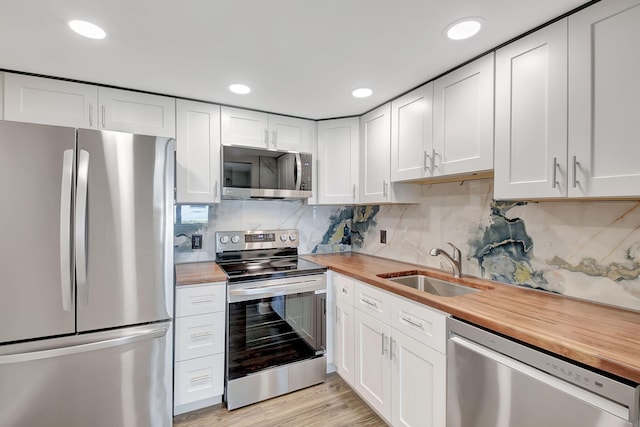 kitchen featuring wood counters, white cabinetry, sink, and appliances with stainless steel finishes