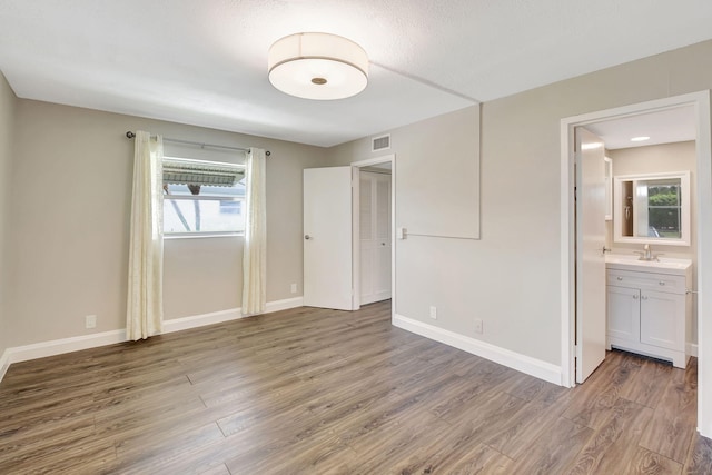 unfurnished bedroom with ensuite bathroom, dark wood-type flooring, and sink