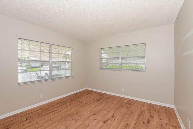 unfurnished room featuring a textured ceiling and light wood-type flooring