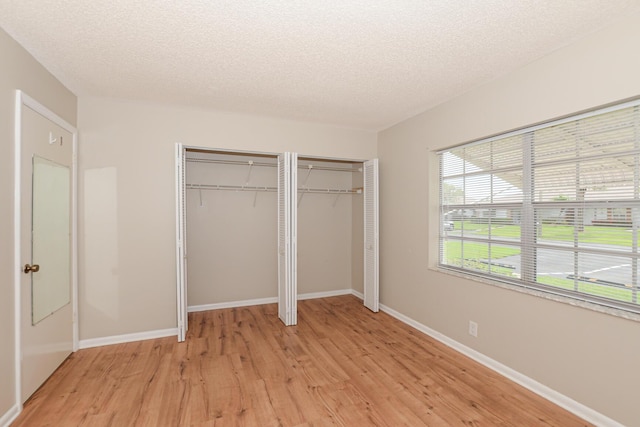 unfurnished bedroom with two closets, a textured ceiling, and light hardwood / wood-style flooring