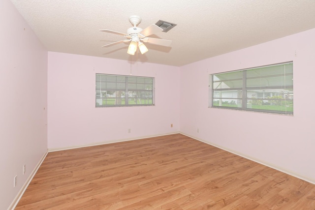 empty room featuring a textured ceiling, light hardwood / wood-style floors, and ceiling fan