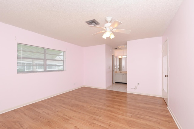 spare room featuring a textured ceiling, light wood-type flooring, and ceiling fan