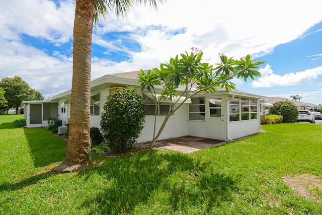 back of property with a lawn and a sunroom