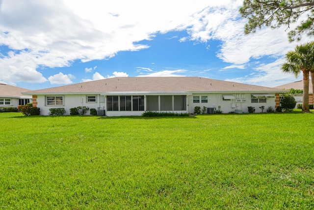 rear view of house featuring a yard, central AC, and a sunroom