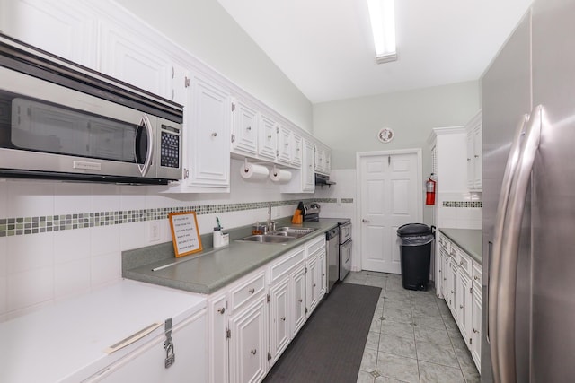 kitchen with white cabinets, sink, stainless steel appliances, and tasteful backsplash