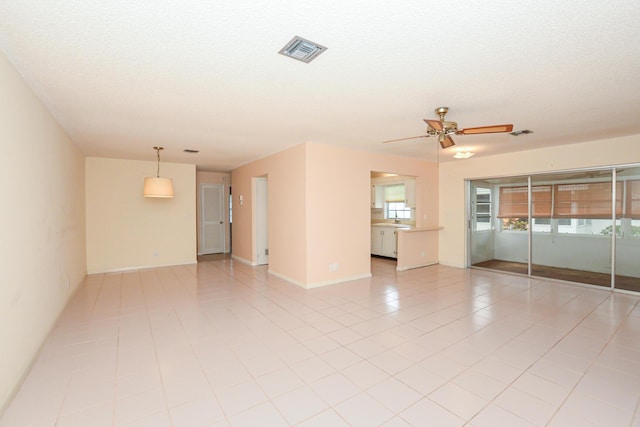 tiled empty room featuring ceiling fan and a textured ceiling