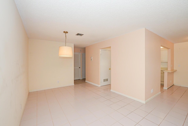 tiled empty room with a textured ceiling