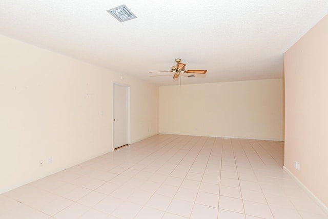 empty room featuring ceiling fan, light tile patterned floors, and a textured ceiling