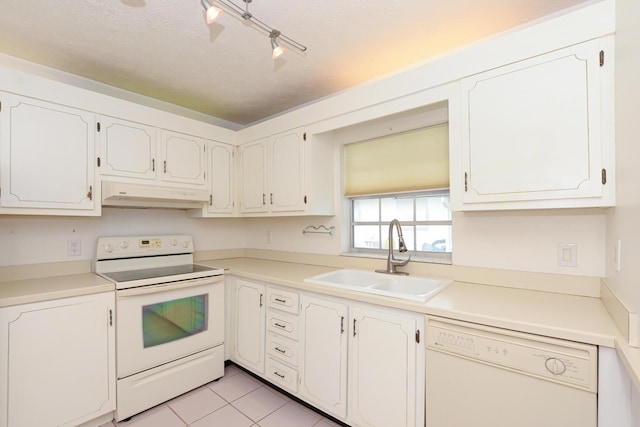 kitchen featuring white appliances, rail lighting, sink, light tile patterned floors, and white cabinetry