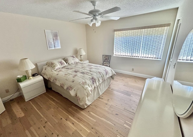 bedroom with ceiling fan, a textured ceiling, and light hardwood / wood-style flooring