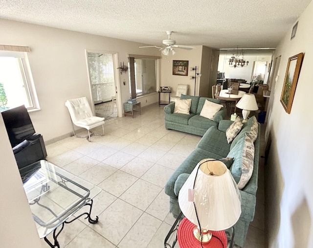 living room featuring light tile patterned floors, ceiling fan with notable chandelier, and a textured ceiling