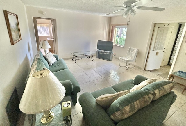 living room with ceiling fan, light tile patterned floors, and a textured ceiling