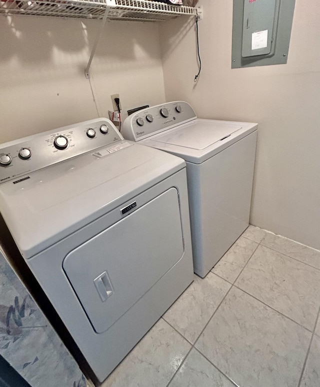 clothes washing area with light tile patterned floors, electric panel, and washing machine and clothes dryer