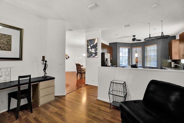 kitchen with stainless steel fridge, dark wood-style floors, a ceiling fan, a sink, and baseboards