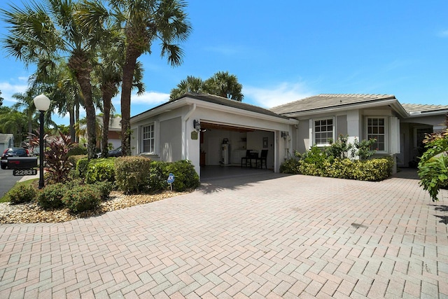 view of front facade featuring a garage, stucco siding, decorative driveway, and a tile roof