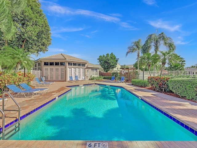community pool with french doors, fence, and a patio