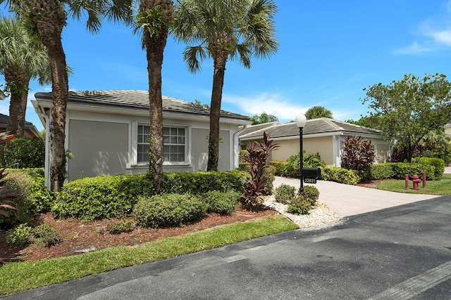 view of front of house featuring stucco siding, driveway, and a tiled roof