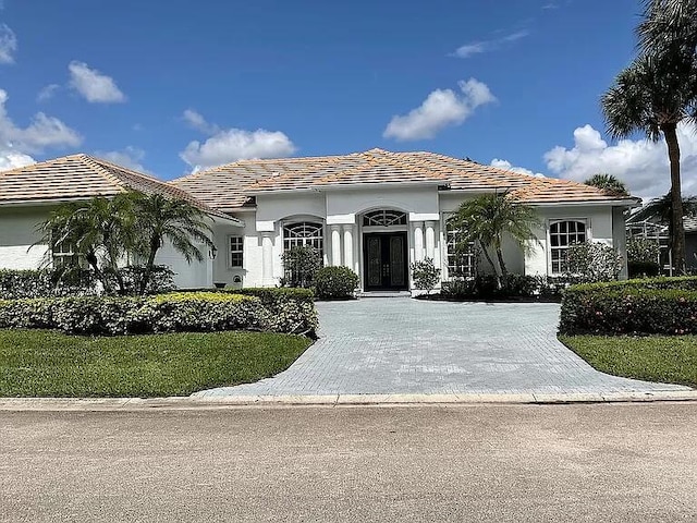 mediterranean / spanish-style house featuring driveway, stucco siding, and a tiled roof