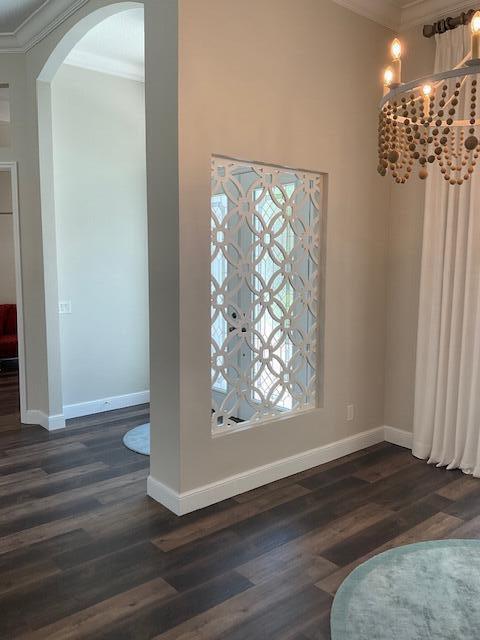 interior space featuring baseboards, arched walkways, and ornamental molding