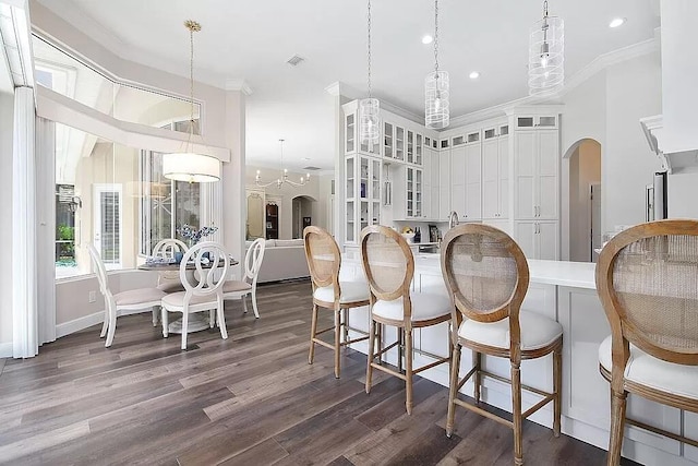 dining area featuring dark wood-style floors, visible vents, arched walkways, and crown molding