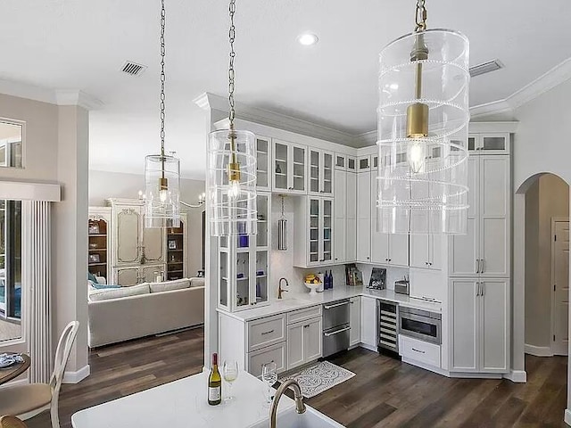 interior space with arched walkways, light countertops, ornamental molding, and dark wood-style flooring