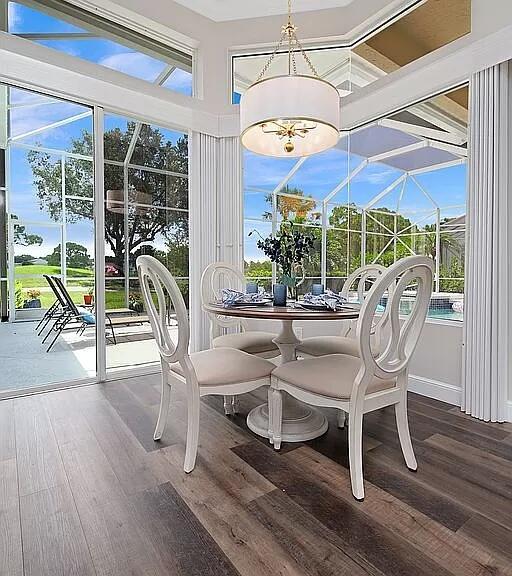 dining area with a chandelier, wood finished floors, a sunroom, and baseboards