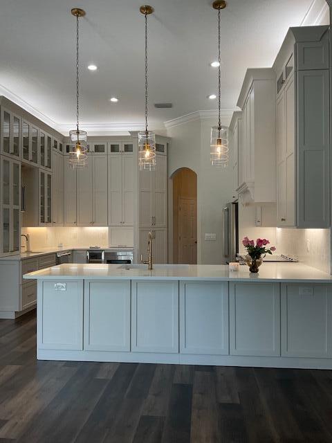 kitchen with arched walkways, light countertops, and dark wood-style floors