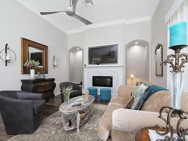 living room featuring arched walkways, visible vents, ornamental molding, a ceiling fan, and wood finished floors