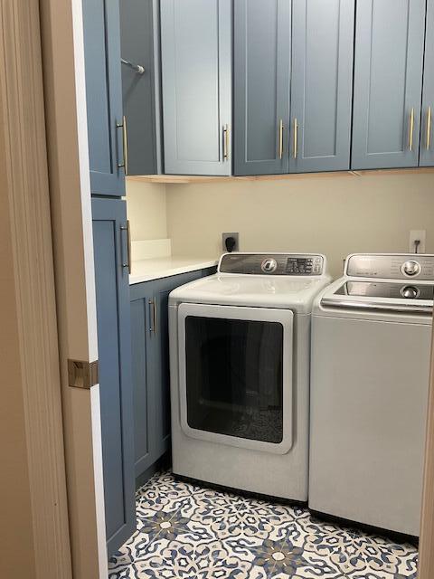 clothes washing area featuring cabinet space and washer and clothes dryer