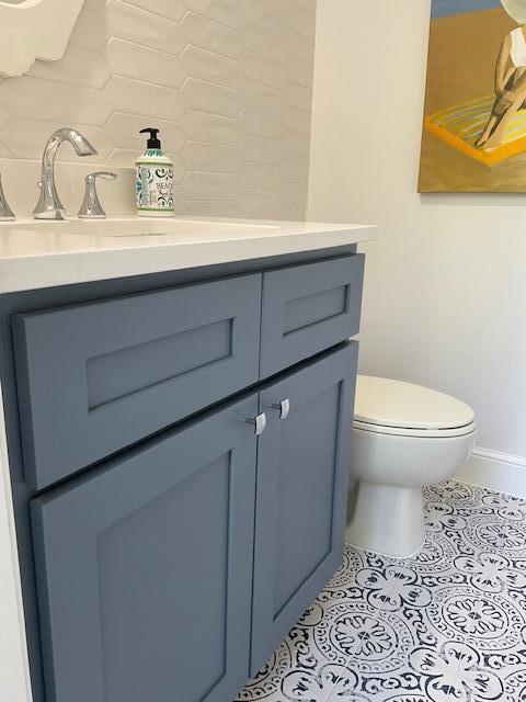 half bathroom featuring toilet, baseboards, vanity, and tile patterned floors