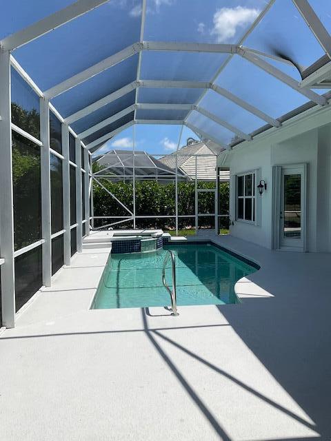 view of pool with a pool with connected hot tub, a patio area, and a lanai