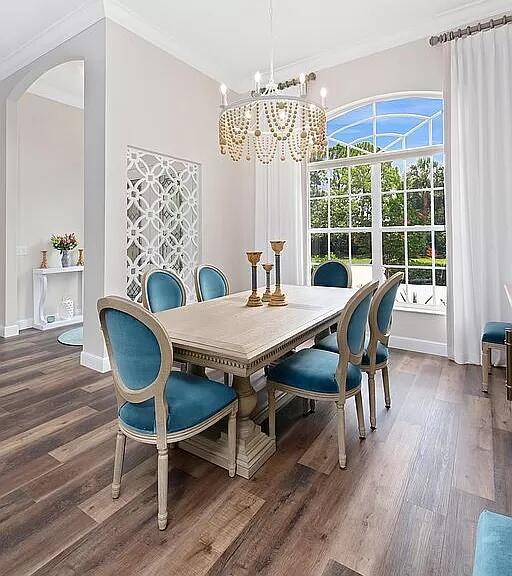 dining space with dark wood-type flooring, arched walkways, a chandelier, and baseboards