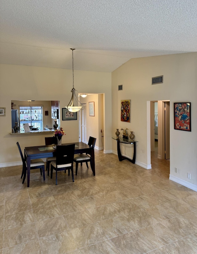 dining room featuring a textured ceiling and high vaulted ceiling