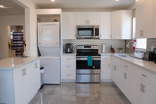 kitchen with light tile patterned flooring, tasteful backsplash, stainless steel appliances, and stacked washing maching and dryer