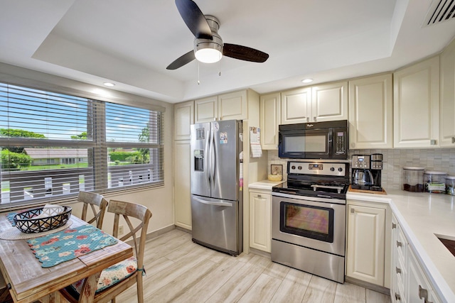 2004 Granada Dr Unit L2, Coconut Creek, FL 33066 - kitchen featuring appliances with stainless steel finishes, a raised ceiling, light countertops, tasteful backsplash, and light wood-style flooring