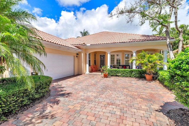 mediterranean / spanish-style home featuring covered porch and a garage