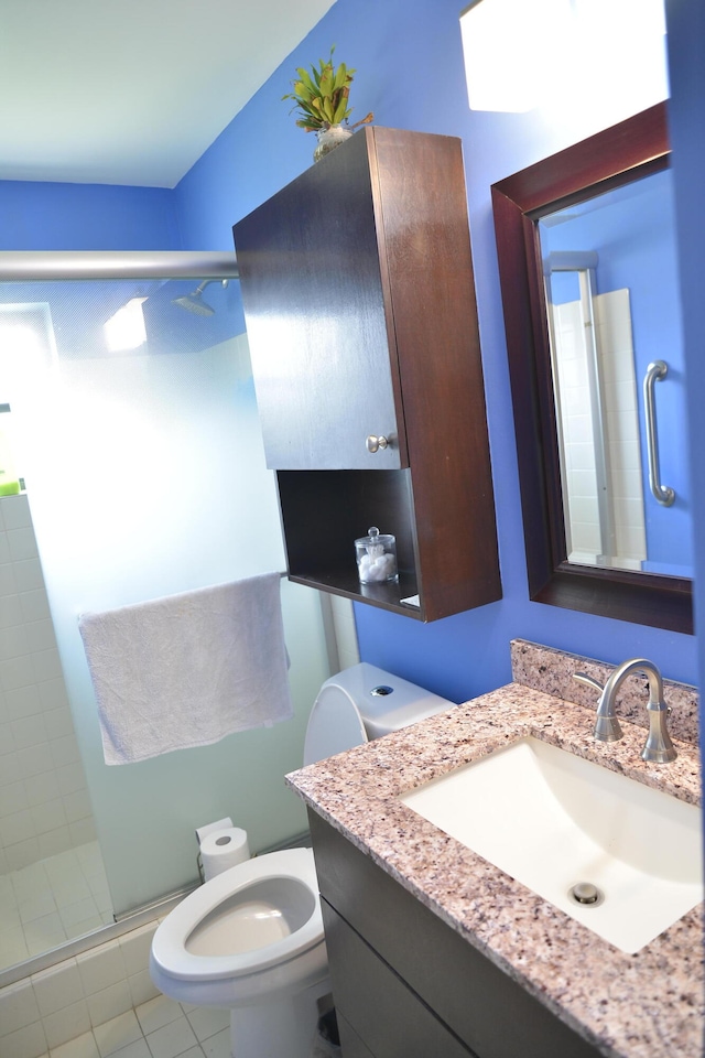 bathroom featuring tile patterned floors, toilet, vanity, and an enclosed shower