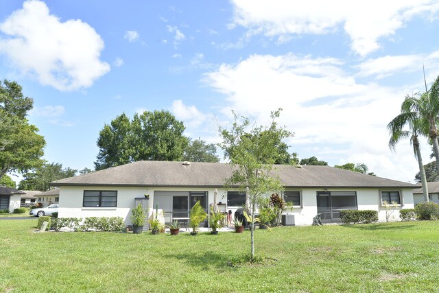 rear view of property featuring a yard and cooling unit