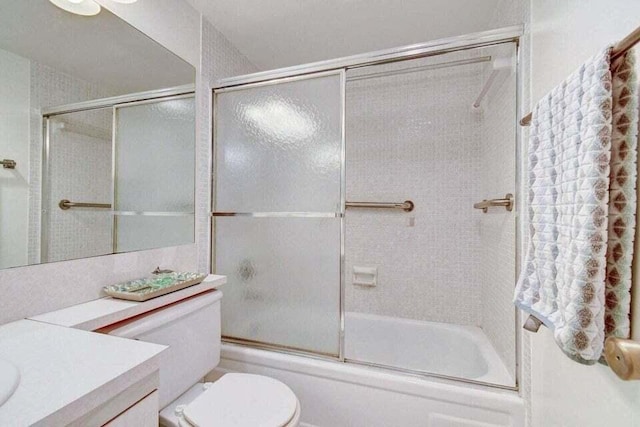 full bathroom featuring shower / bath combination with glass door, toilet, and vanity