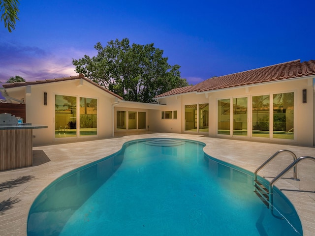 pool at dusk featuring a patio