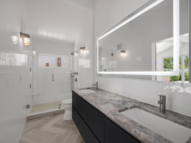 bathroom featuring toilet, vanity, tile walls, and a shower with door