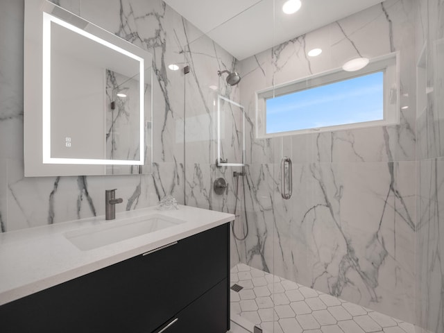 bathroom with walk in shower, vanity, and tile walls