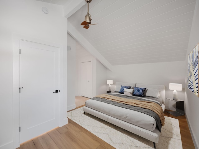 bedroom featuring ceiling fan, light hardwood / wood-style flooring, and vaulted ceiling with beams